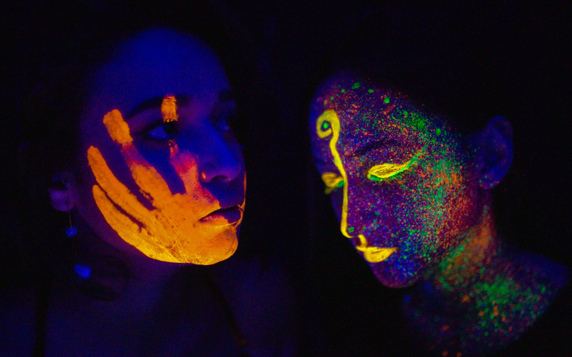 Two women, glowing in the dark, one seemingly attuning to the other