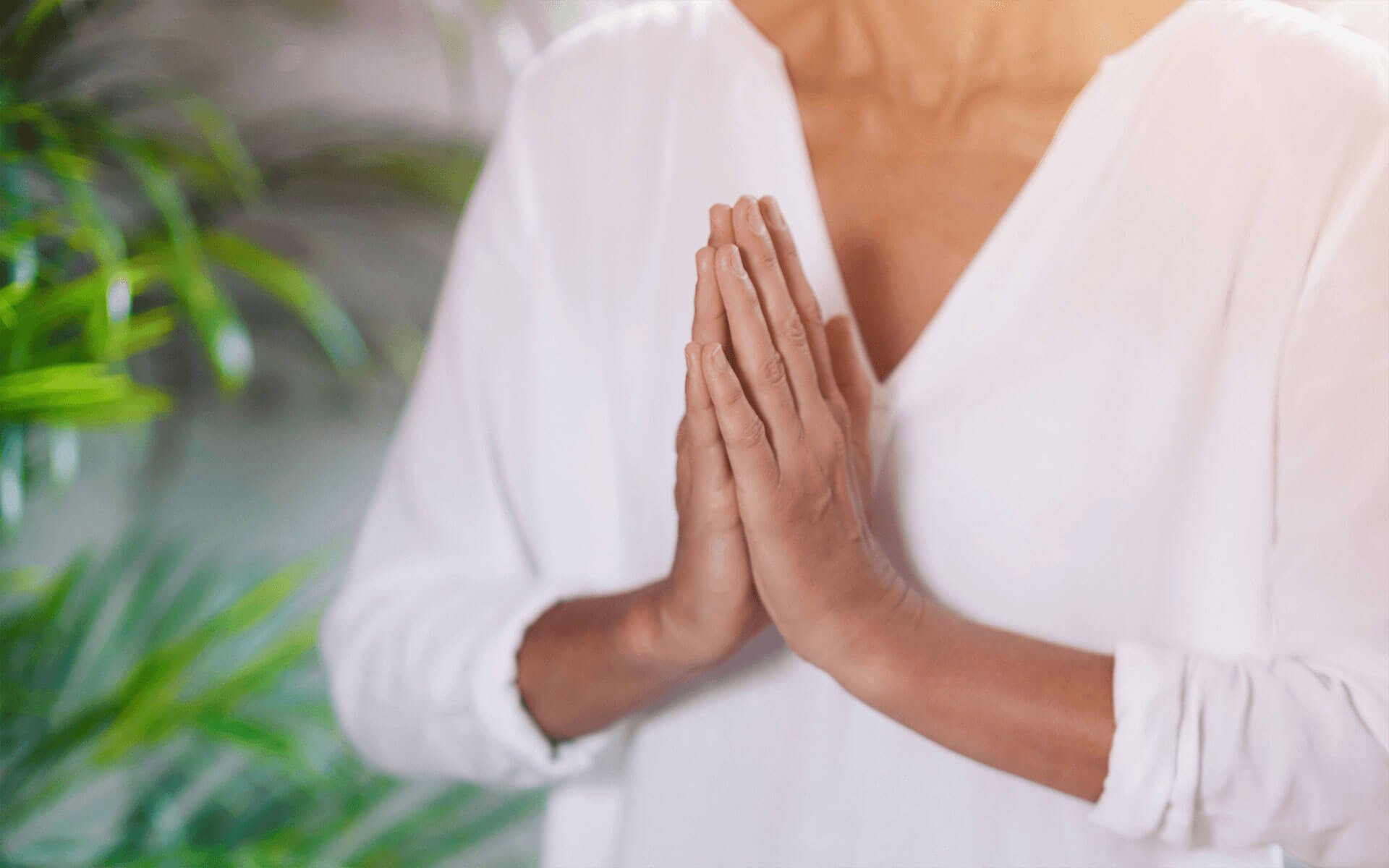 Reiki master's hands in a prayerful position in front of the heart