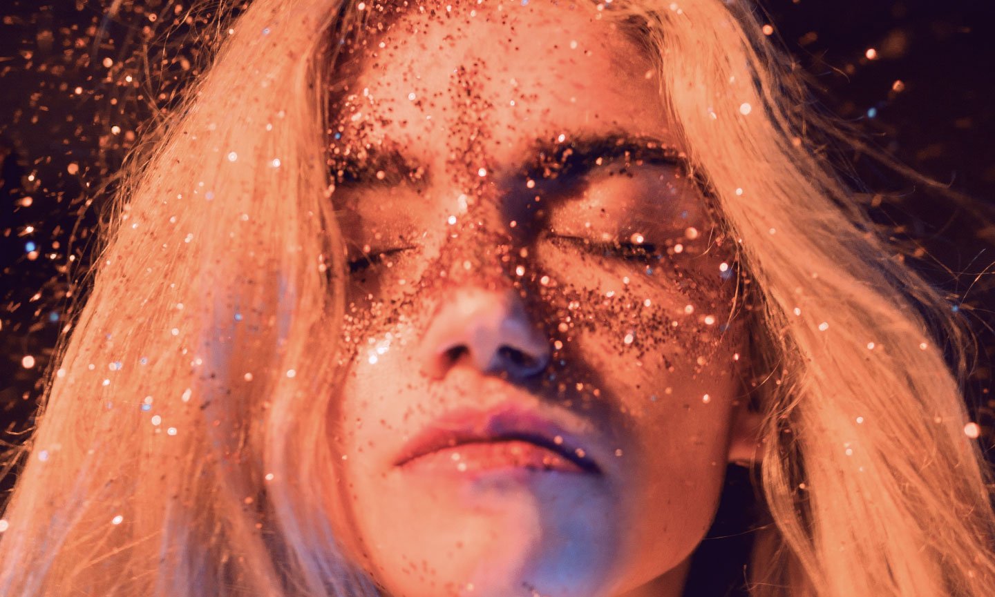 Face of a young woman with sparkles, eyes closed, representing receiving healing magic