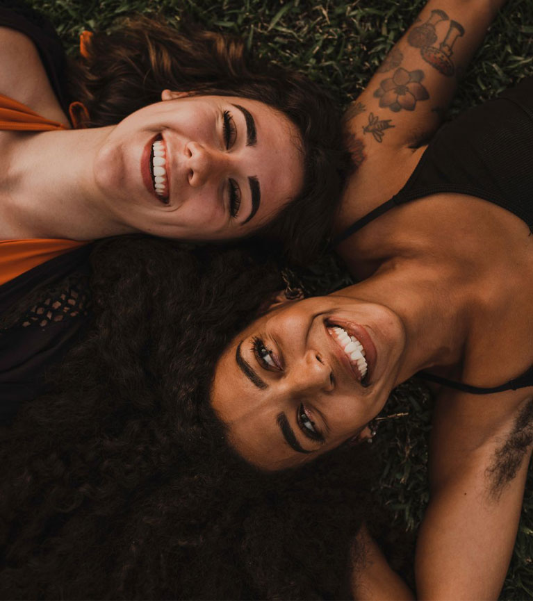 Two women lying on the grass, connecting and smiling